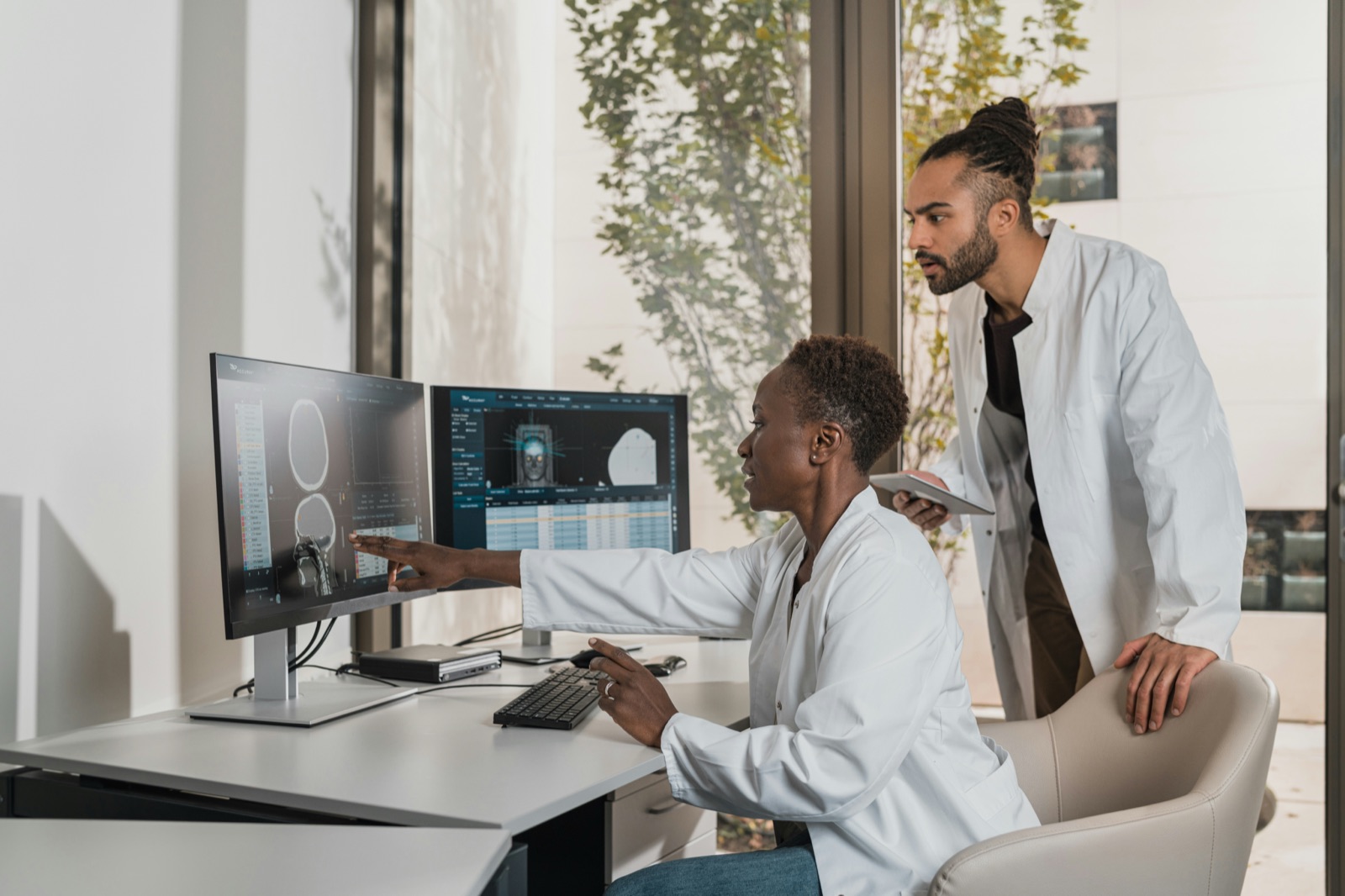 Two radiologists discussing scans on screen